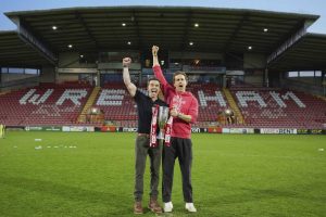 Wrexham co-owners Rob McElhenney, left, and Ryan Reynolds pose with trophy at the end of the English League One soccer match between Wrexham and Charlton Athletic at the Racecourse ground in Wrexham, Wales, Saturday, April 26, 2025. (AP Photo/Jon Super)